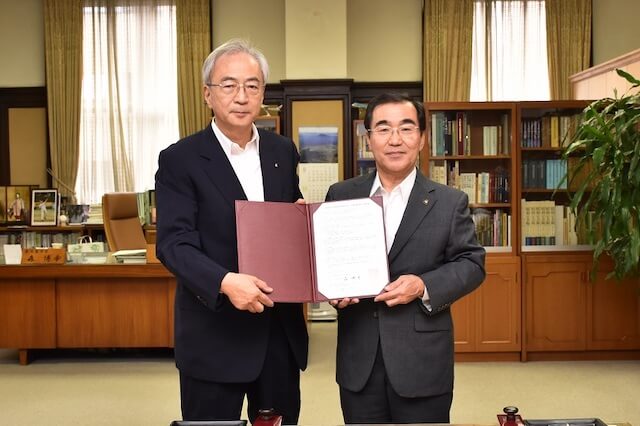協定書を手にする野呂学長(左)と森市長(右)